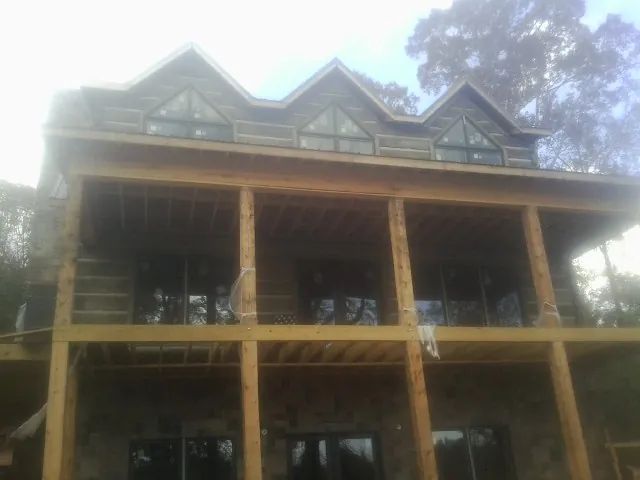 Dormers and porch framing on a large log home under construction — Roof Coating work by our crew in Eastover
