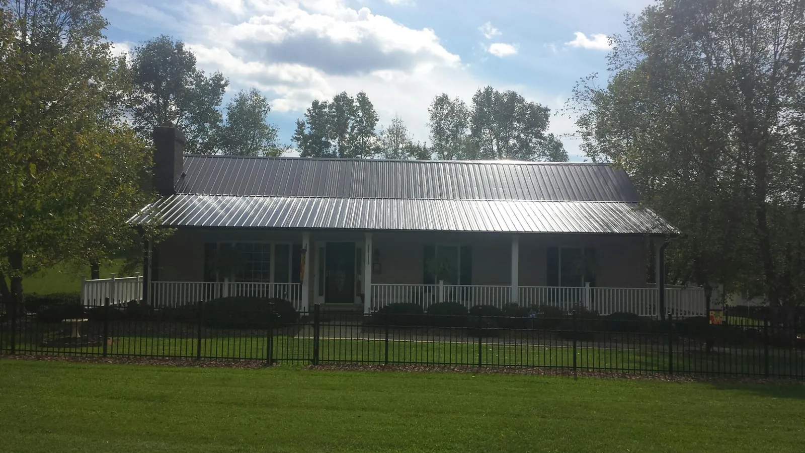 Gray metal roof on a brick ranch with a full width front porch — Gutter Guard Installation work by our crew in Eastover