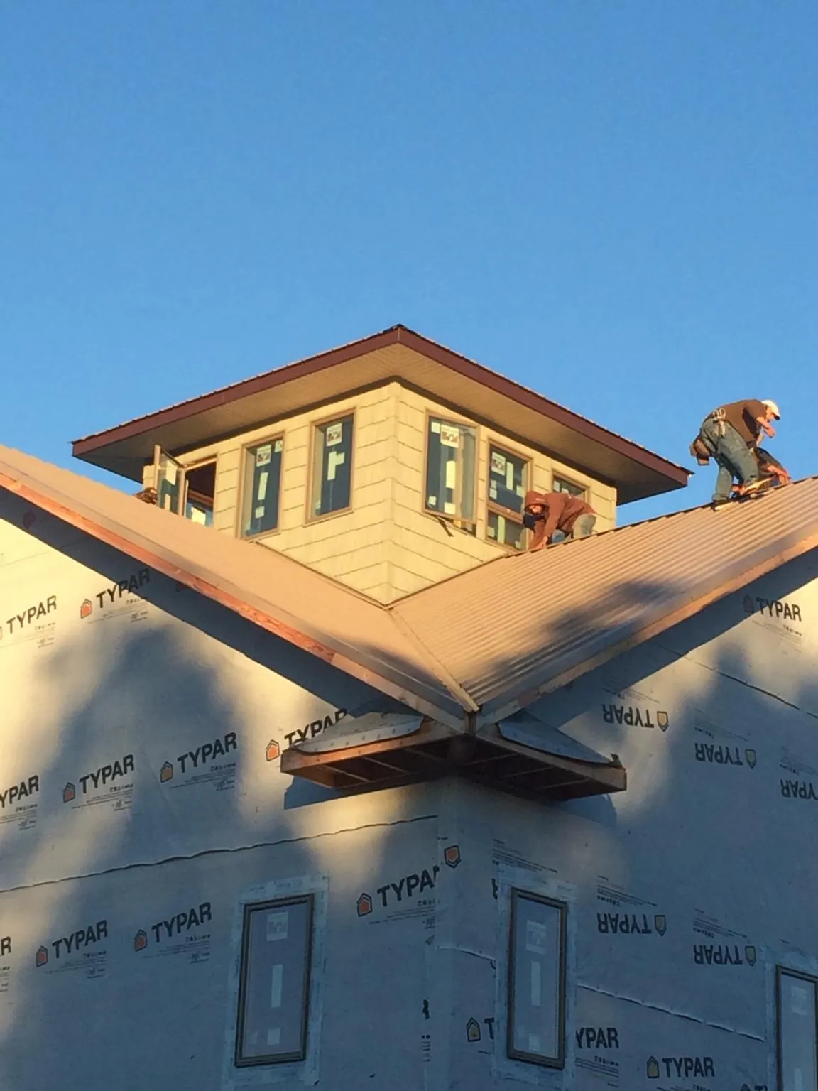 Roofers working around a rooftop cupola on a new metal roof at sunset — Roof Waterproofing in Eastover by Roofing Brothers